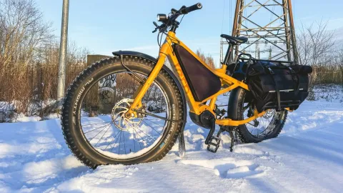 Highland yellow Orox ebike with panniers parked on snow during winter ride