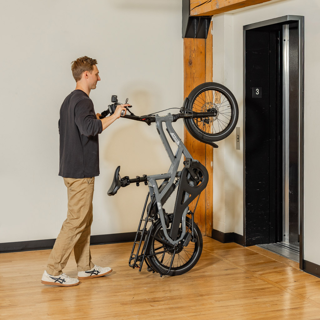 A guy rolling Tern HSD cargo e-bike vertically through the elevator
